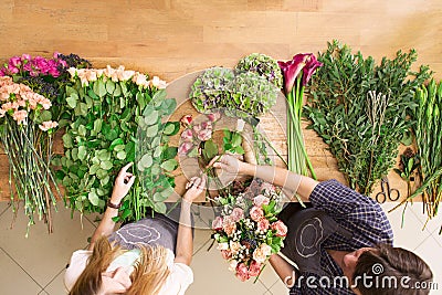 Florist and assistant in flower shop delivery make rose bouquet, table top view Stock Photo
