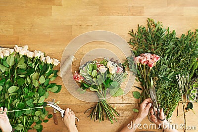 Florist and assistant in flower shop delivery make rose bouquet, table top view Stock Photo