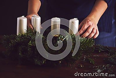 Woman attaches candle holder on a Christmas wreath Stock Photo