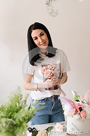 the florist collects a bouquet of flowers smiling brunette girl in a white t-shirt with flowers Stock Photo