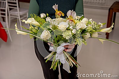 The florist creates a floral arrangement of roses, lilacs, callas, carnations, hydrangeas, brasica, alstroemeria, ornithogalum, Stock Photo