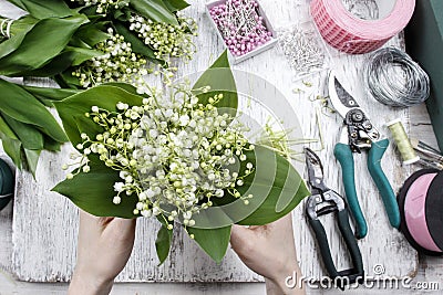 Florist at work. Woman making bouquet of lily of the valley flow Stock Photo