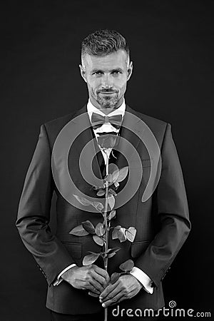 Floristics for ceremonies. Rich groom at wedding. handsome man in tuxedo with bowtie. red rose symbol of passion and Stock Photo