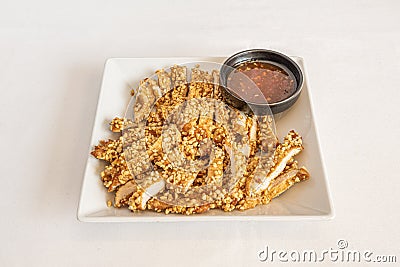 Flour-drenched chicken breast fillets and chopped almonds, with sweet and sour sauce to dip Stock Photo