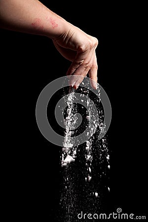 Flour in hand falling down on black background like snow Stock Photo