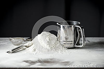 Flour on a kitchen table on a black moody background in the morning light. Space for advertising products. Stock Photo
