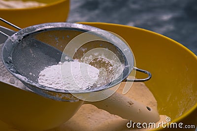 Flour sifting through a metal sieve for a baking. Close up Stock Photo