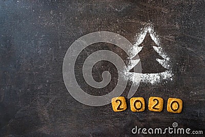 Flour Silhouette Christmas Tree with cookies digits 2020 on dark background with copyspace. Delicious bakery sweet confectionery Stock Photo
