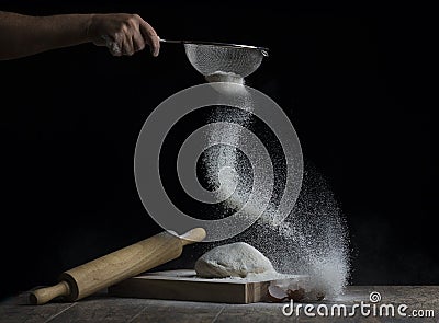 Flour is sprinkled over a ball of dough on a wooden board with r Stock Photo
