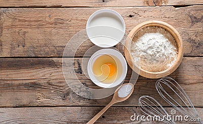 The flour in a wooden bowl, egg, milk and whip for beating. Stock Photo