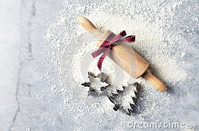 A floured marble work surface, cutters and a rolling pin with red ribbon. Christmas baking. Flatlay. Copy space Stock Photo