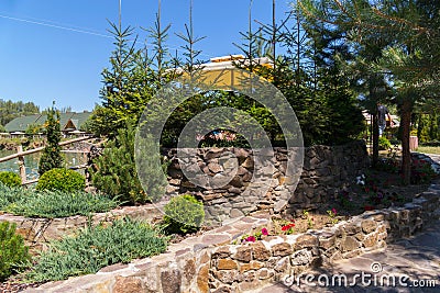 Flower beds in the park laid out of stone with growing on them small Christmas trees Stock Photo