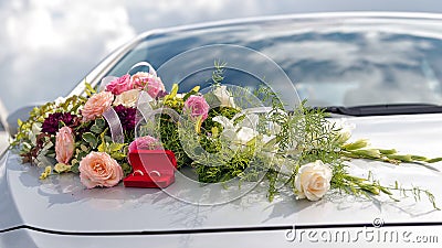 Flower decoration and a ring set on gray wedding car bonnet. Stock Photo