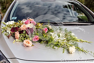 Flower decoration and a ring set on gray wedding car bonnet. Stock Photo