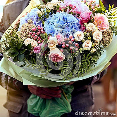 Flower delivery on order. Courier holds a beautiful bouquet of flowers for the customer. Service concept Stock Photo