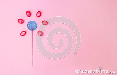 Flower made of lollipop and candies on pink background with copy space. Minimal concept Stock Photo