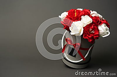 Flowers in bloom: A bouquet of red and white roses in a gray round box on a gray background. Stock Photo