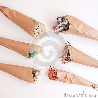 Flowers in bunches, herbs, dried flowers in kraft packaging on white background, top view, space for text. Stock Photo