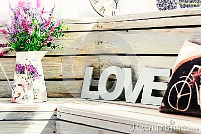 Flowers in a vase with the word Love with a pillow with a picture of a bicycle on the background of wooden boards Stock Photo