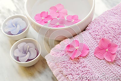 Flowers in a water bowl with a candle and a towel Stock Photo