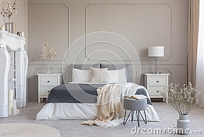 Flowers on white wooden nightstand table in luxury bedroom interior with king size bed Stock Photo