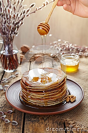 Flowing honey on stack of homemade traditional pancakes with nuts Stock Photo
