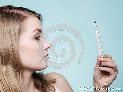 Flu. Sick girl with fever checking thermometer. Stock Photo