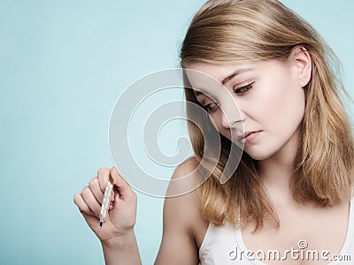 Flu. Sick girl with fever checking thermometer. Stock Photo