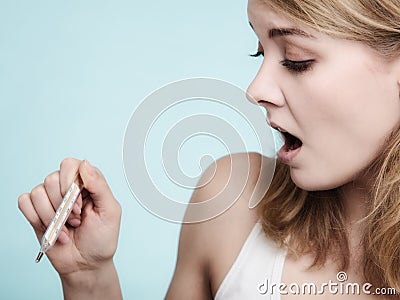 Flu. Sick girl with fever checking thermometer. Stock Photo