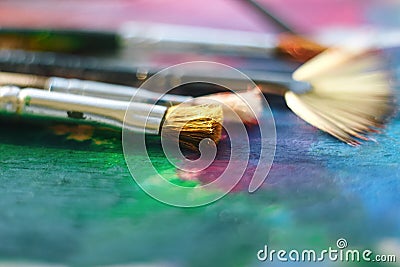 The fluffy brush lies on the palette painted with multi-colored oil Stock Photo