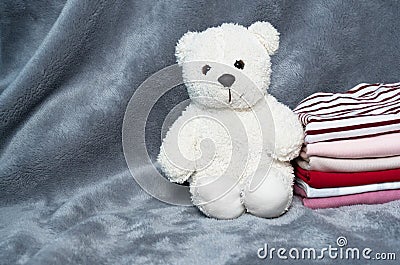 Fluffy white small bear with cloth stack whit grey fur home laundry background Stock Photo