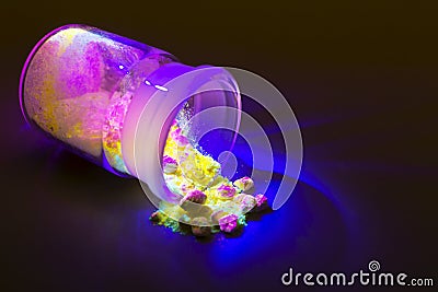 Fluorescent organic materials of red, yellow and green color for production OLED inside glass bottle in UV light. Stock Photo