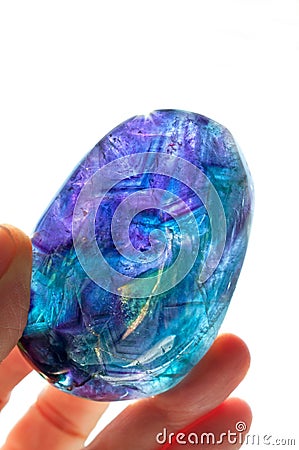 Fluorite crystal hand held in sunlight with purple, blue and turquoise colors Stock Photo