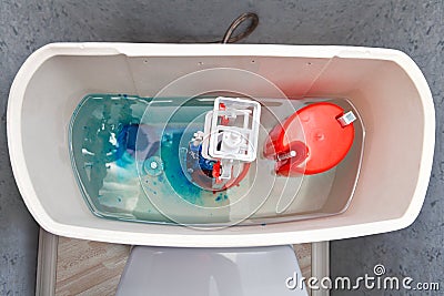 Flush mechanism inside cistern of toilet, blue water tablet dissolves. Stock Photo