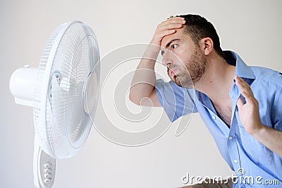 Flushed man feeling hot in front of a fan Stock Photo