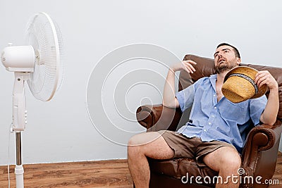 Flushed man feeling hot in front of a fan Stock Photo