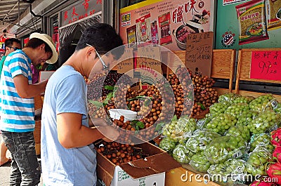 Flushing, NY: Worker with Longan Fruits Editorial Stock Photo