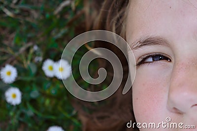 Half part of the face of a little girl lying down on the grass Stock Photo