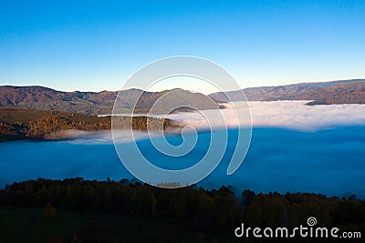 Flying above the clouds in dawn. Misty morning in the valley, aerial view Stock Photo