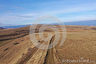 Flying above a countryside dirt road and meadow, aerial view Stock Photo