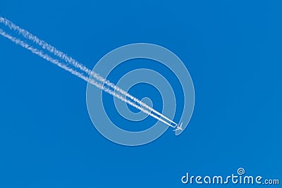 Flying airplane on a journey through the blue sky with a long white smoking exhaust plume and jetwash show international transport Stock Photo