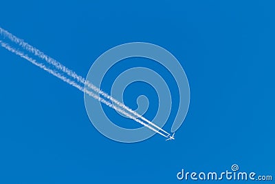 Flying airplane on a journey through the blue sky with a long white smoking exhaust plume and jetwash show international transport Stock Photo