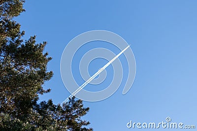 Flying airplane on a journey through the blue sky with a long white smoking exhaust plume and jetwash show international transport Stock Photo