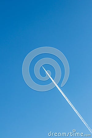 Flying airplane on a journey through the blue sky with a long white smoking exhaust plume and jetwash show international transport Stock Photo