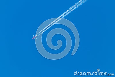 Flying airplane on a journey through the blue sky with a long white smoking exhaust plume and jetwash show international transport Stock Photo