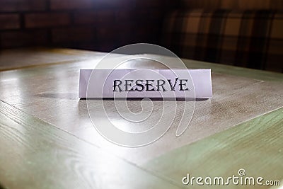 The flying around the plate is reserved, which stands on the wooden table in the restaurant. Reservation of a place in the cafe. Stock Photo