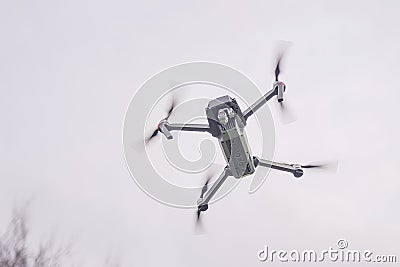 A flying drone against a cloudy sky in cloudy weather takes pictures of the surface of the earth Stock Photo