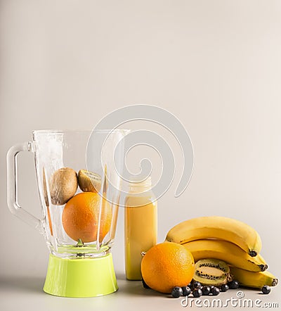 Flying ingredients for making smoothies from oranges, kiwi and bananas, vegetarian healthy food, fruit lined around a green blende Stock Photo