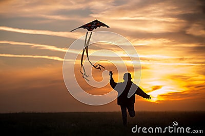 Flying a kite. The boy runs across the field with a kite. Silhouette of a child against the sky. Bright sunset Stock Photo