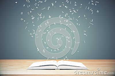 Flying letters from the opened book on wooden table Stock Photo